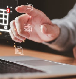 Hand pointing at floating ecommerce icons including a shopping cart