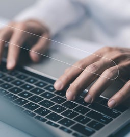 Hands typing at a laptop keyboard with a search bar image floating above
