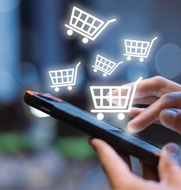Shopping cart icons floating out of a mobile phone