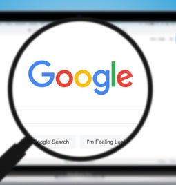 Magnifying glass hovering over a laptop screen showing the Google search homepage