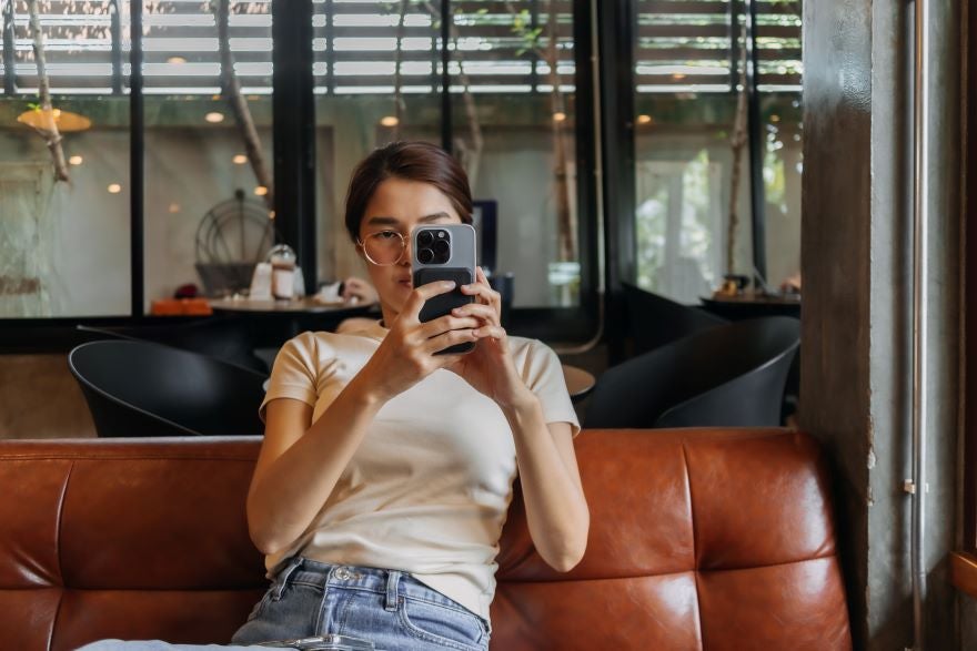 Woman sat on a sofa holding up a phone to take a photo