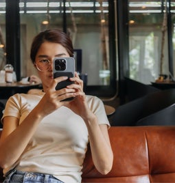 Woman sat on a sofa holding up a phone to take a photo