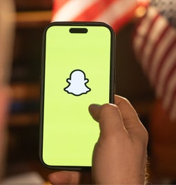 hand holding phone with snapchat logo on