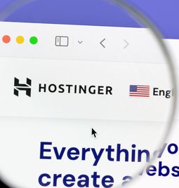 Magnifying glass hovering over the Hostinger logo on the desktop homepage