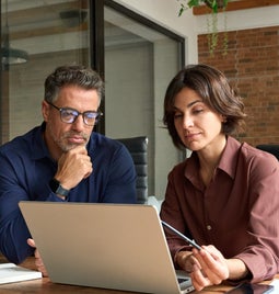 Man and woman working together at a laptop in an office space