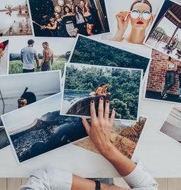 A hand sorting printed images on a table