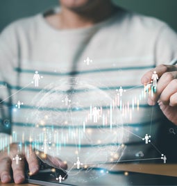 Person monitoring a rising chart with little human figures scattered throughout