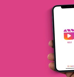 Photo of a hand holding a smartphone with the Instagram Reels logo on screen