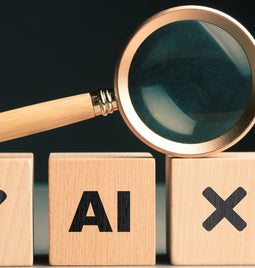 A magnifying glass rests on wooden blocks labeled with a checkmark, 