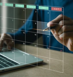 See through calendar visual floating above a laptop with a person pointing to a date