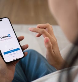 Woman holding a mobile phone with the LinkedIn login page on screen