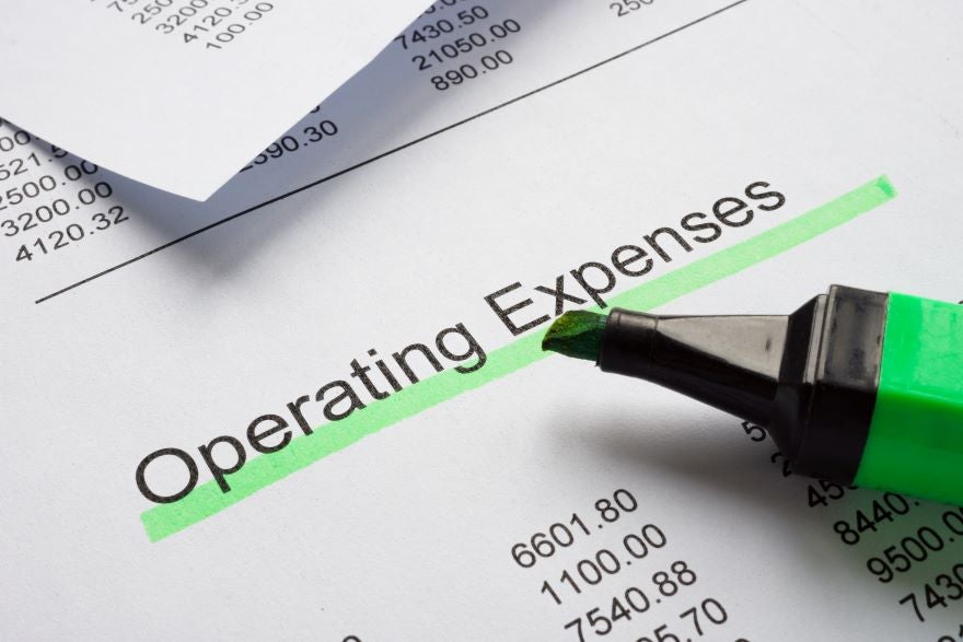 A close-up of a highlighter marking "Operating Expenses" on a printed financial document with listed numbers and notations.