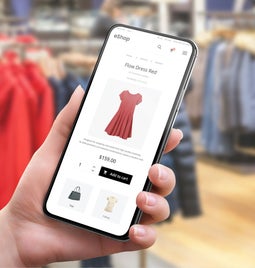 Hand holding a smartphone with a product page for a red dress on screen