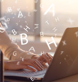 Woman typing at a laptop with floating letters around her hands