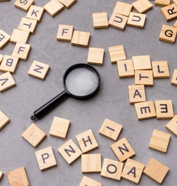 Magnifying glass surrounded by scrabble tiles