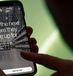 Person holding smartphone displaying Shopify website with the message: 