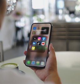 man looking at iPhone folder with seven social media apps inside