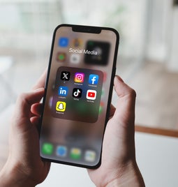 A person holds a smartphone displaying a folder labeled 