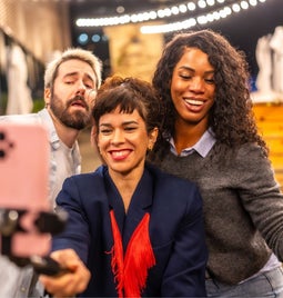 Three people posting in front of a phone on a tripod