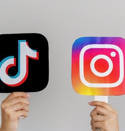 hands holding two lollypop sticks with tiktok and instagram logos on