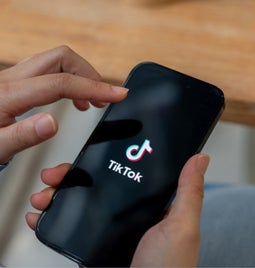 Person holding a phone with the TikTok logo on display