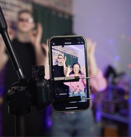 A man and a woman dance on a smartphone camera. A view of the phone screen standing on a tripod