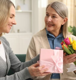 Daughter sharing gifts and flowers with her mother for Mother's Day