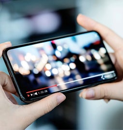 Hands holding a smartphone with a video playing on screen