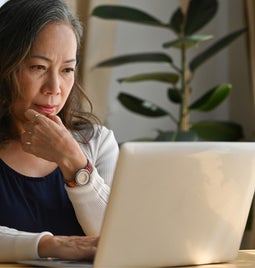 Woman looking thoughtful in front of laptop
